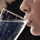 Person sipping on a glass of sparkling water